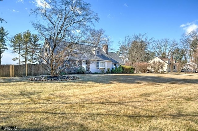 view of property exterior featuring fence, a chimney, and a lawn