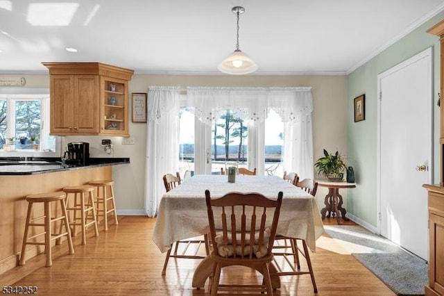 dining room featuring ornamental molding, light wood finished floors, and baseboards