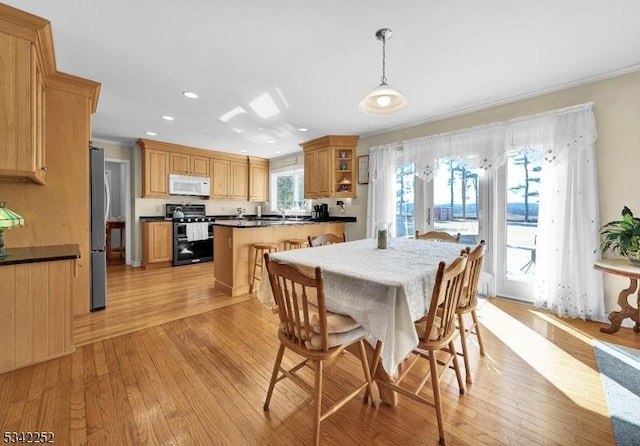 dining area featuring light wood-type flooring, crown molding, and recessed lighting