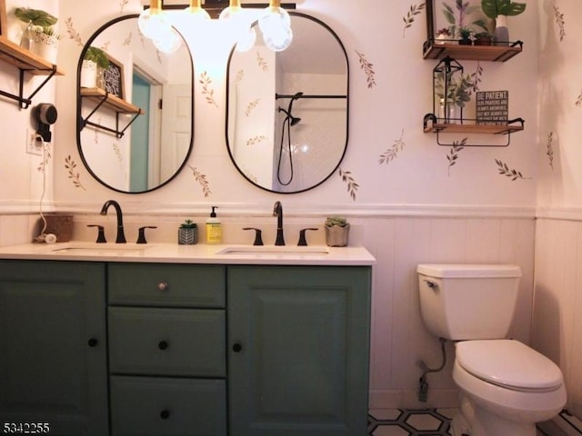 full bathroom with toilet, a wainscoted wall, double vanity, and a sink