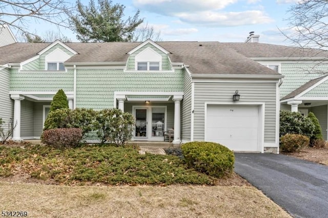 townhome / multi-family property with french doors, roof with shingles, driveway, and an attached garage