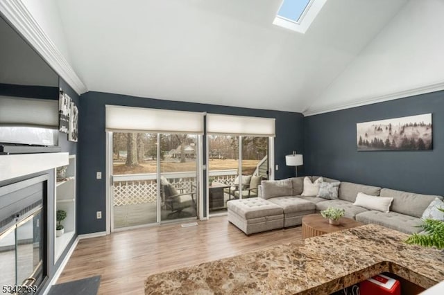 living room featuring lofted ceiling with skylight, a glass covered fireplace, and wood finished floors