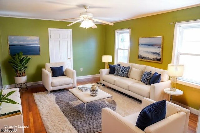 living room with ornamental molding, a ceiling fan, baseboards, and wood finished floors