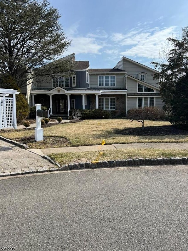 shingle-style home with covered porch and a front lawn