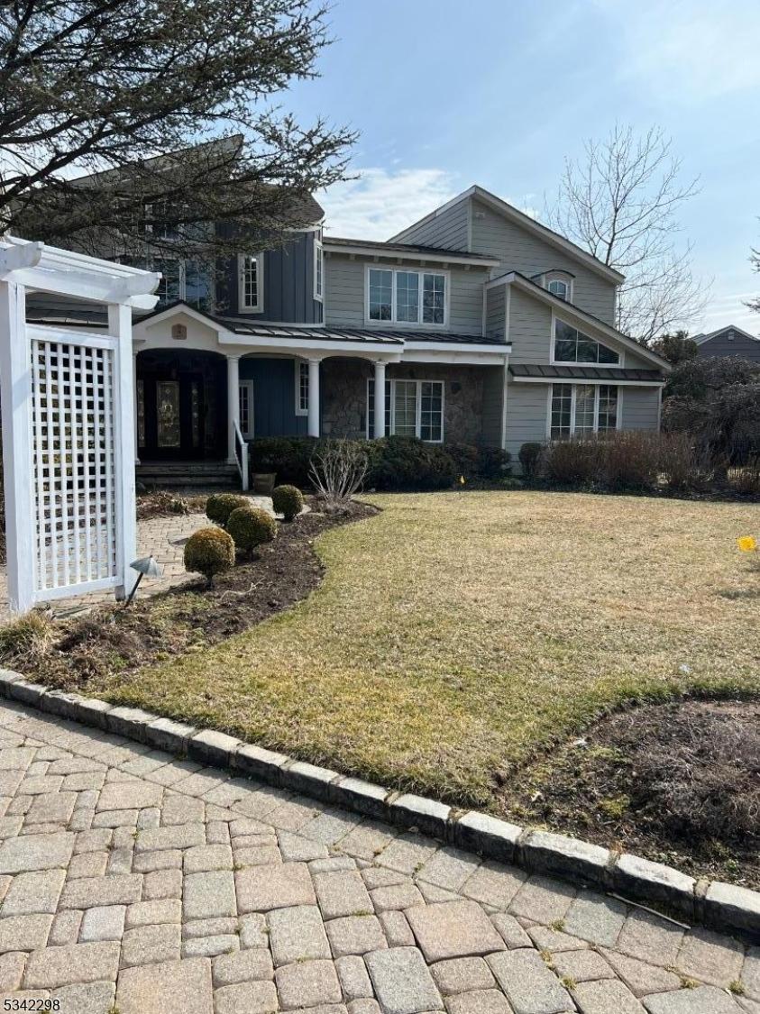 view of front facade with covered porch, stone siding, board and batten siding, and a front yard