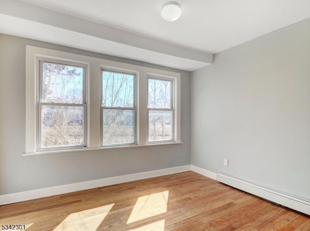 empty room with baseboards, light wood-style floors, and a baseboard radiator