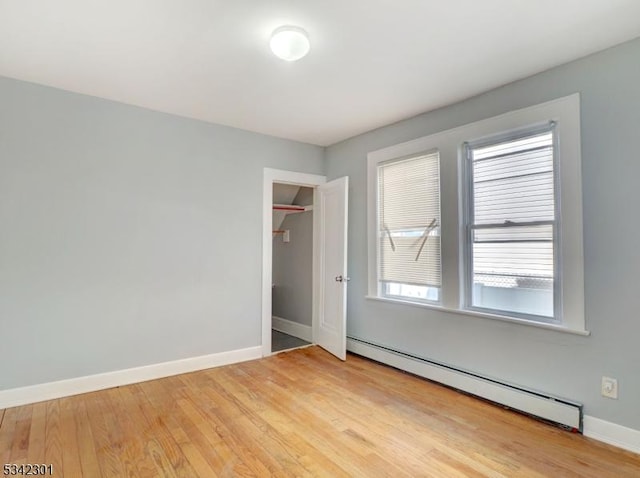 unfurnished bedroom featuring light wood-type flooring, baseboards, and a baseboard radiator