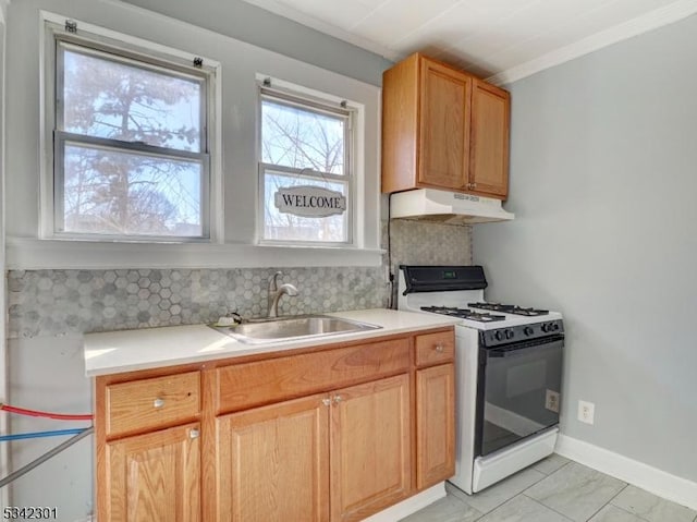 kitchen featuring range with gas stovetop, a sink, decorative backsplash, light countertops, and under cabinet range hood