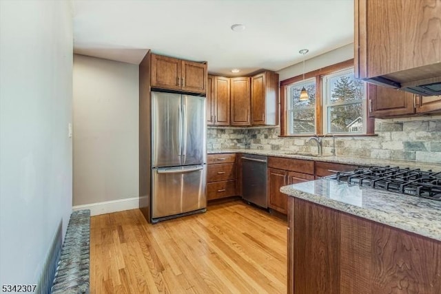 kitchen with brown cabinets, decorative backsplash, stainless steel appliances, and a sink