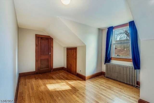 bonus room with lofted ceiling, baseboards, wood finished floors, and radiator