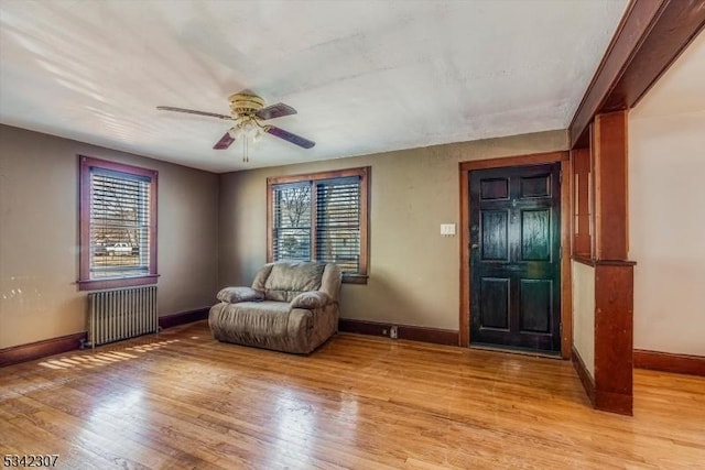 unfurnished room featuring baseboards, a ceiling fan, light wood-style flooring, and radiator