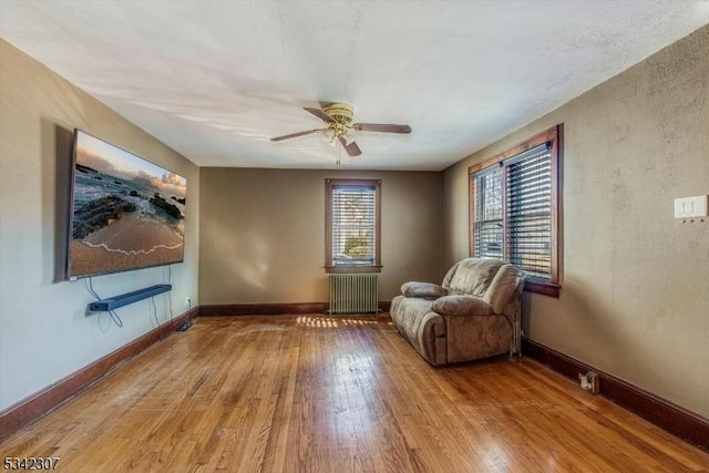 unfurnished room with baseboards, ceiling fan, hardwood / wood-style floors, and radiator