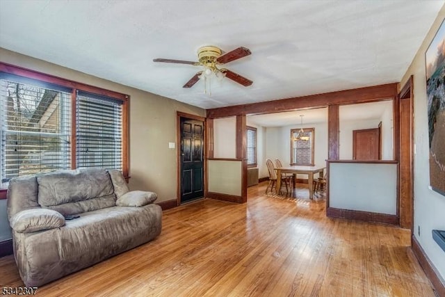 living area featuring light wood finished floors, ceiling fan, and baseboards