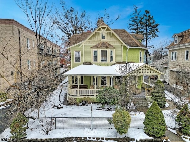 view of front of house featuring a fenced front yard, a chimney, a porch, and board and batten siding