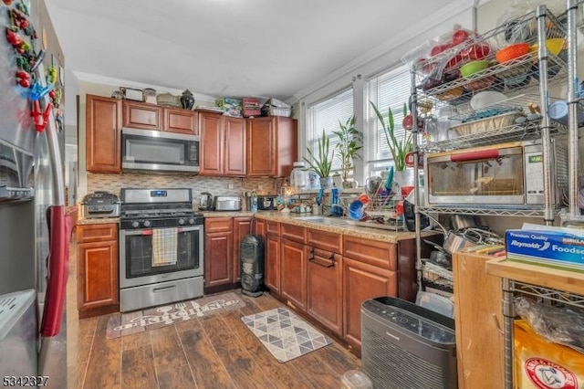 kitchen featuring decorative backsplash, light stone counters, dark wood-style flooring, stainless steel appliances, and a sink