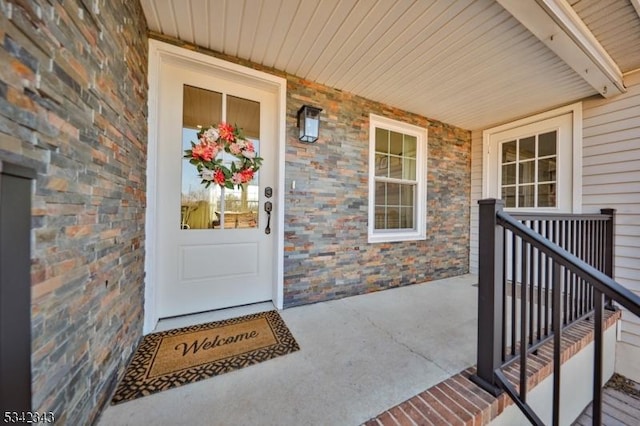 view of exterior entry featuring a porch and brick siding