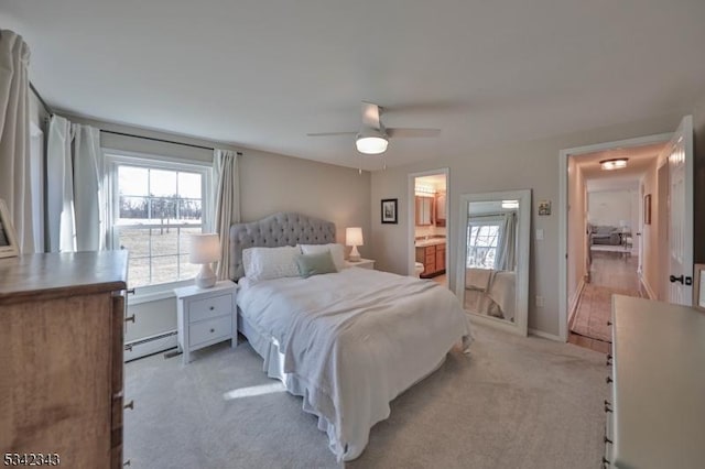 bedroom featuring light carpet, multiple windows, baseboard heating, and ensuite bathroom