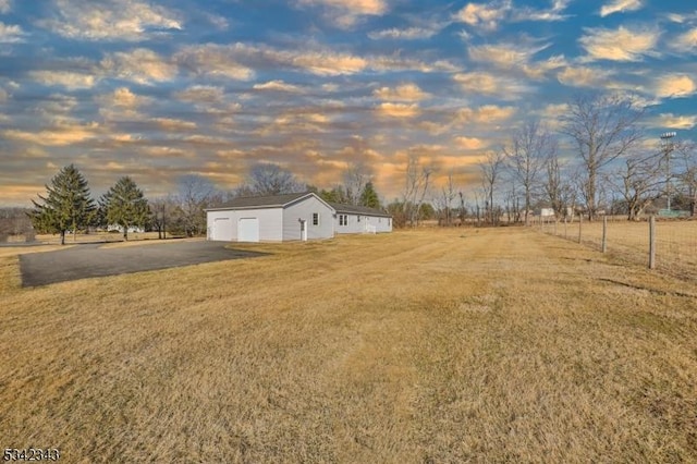 view of yard with a rural view, a detached garage, and an outdoor structure