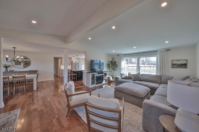 living area with decorative columns, recessed lighting, lofted ceiling with beams, an inviting chandelier, and wood finished floors