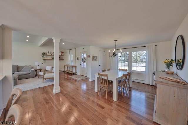 dining room with a chandelier, recessed lighting, light wood-type flooring, and ornate columns