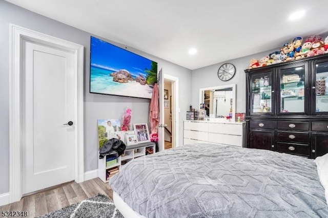 bedroom with wood finished floors, baseboards, and ensuite bathroom