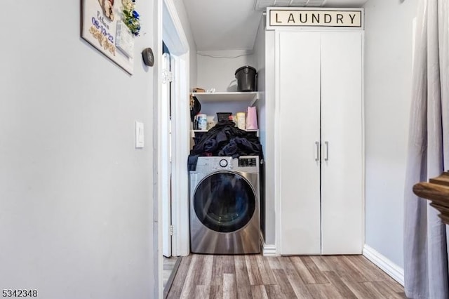 clothes washing area featuring laundry area, washer / clothes dryer, baseboards, and wood finished floors