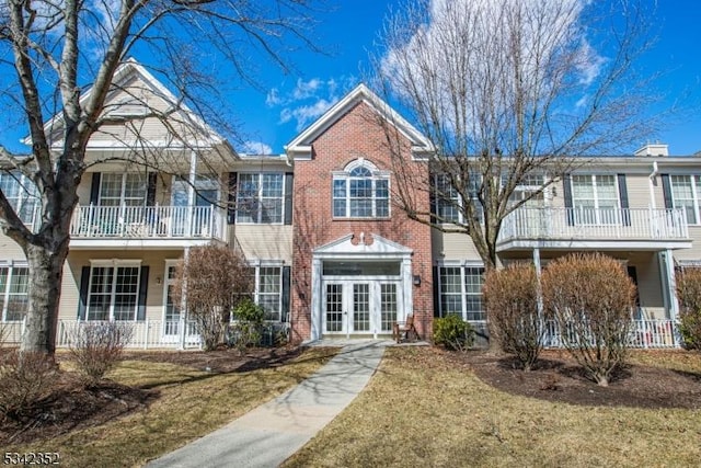 view of front of house with french doors, brick siding, and a balcony