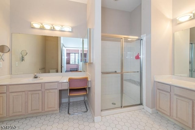 bathroom featuring a sink, baseboards, two vanities, and a shower stall