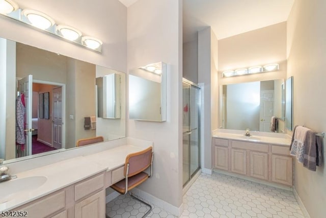 bathroom featuring two vanities, baseboards, a stall shower, and a sink