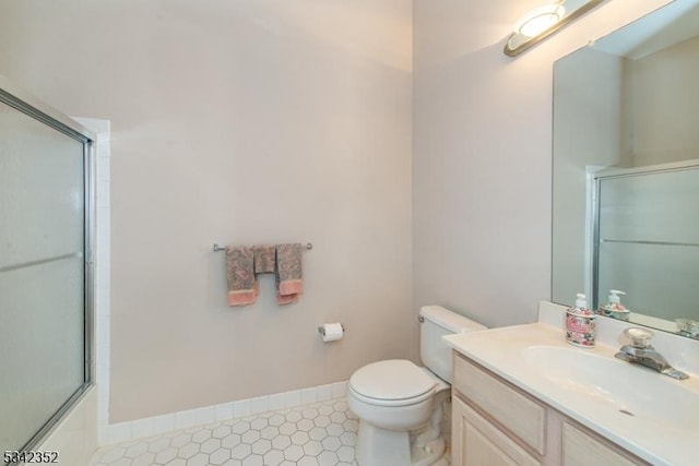 full bathroom with toilet, vanity, baseboards, and shower / bath combination with glass door