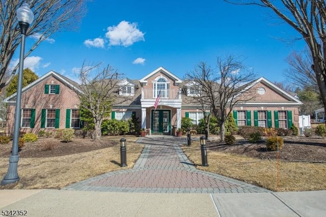 view of front of house with a balcony, french doors, and brick siding