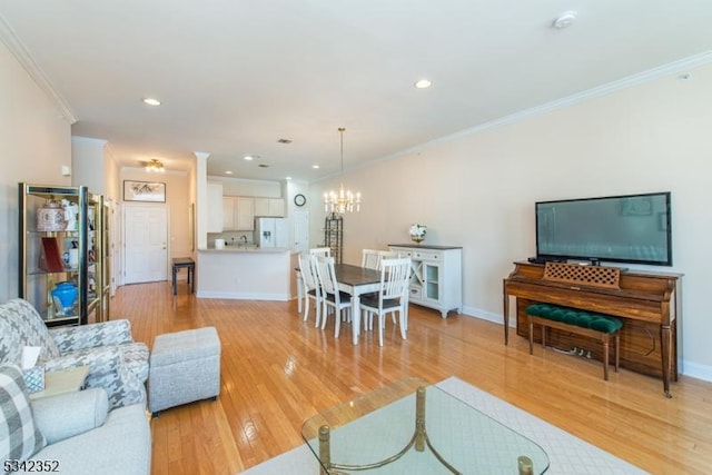 living area with crown molding, light wood-style flooring, baseboards, and a chandelier