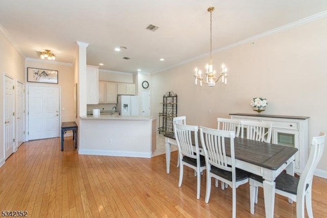 dining room featuring baseboards, visible vents, crown molding, light wood-type flooring, and a chandelier