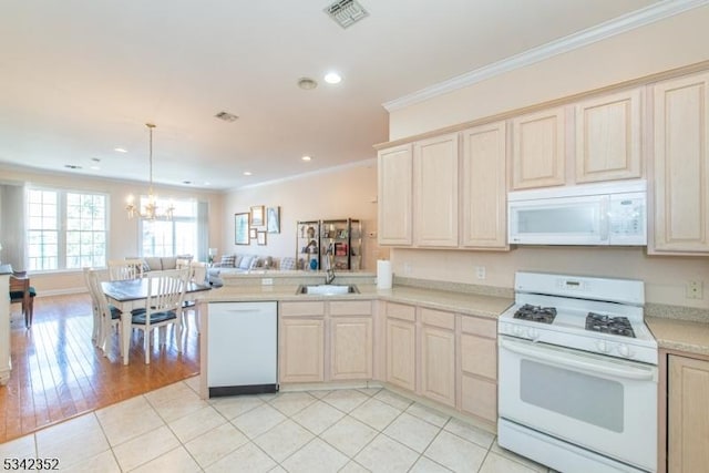 kitchen featuring white appliances, visible vents, ornamental molding, a sink, and open floor plan