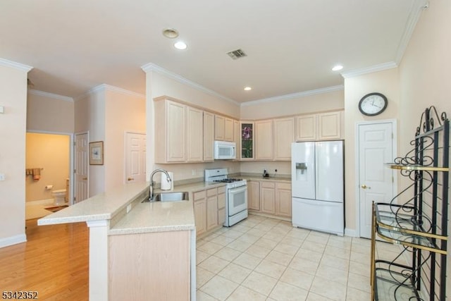 kitchen featuring white appliances, ornamental molding, a peninsula, and a sink