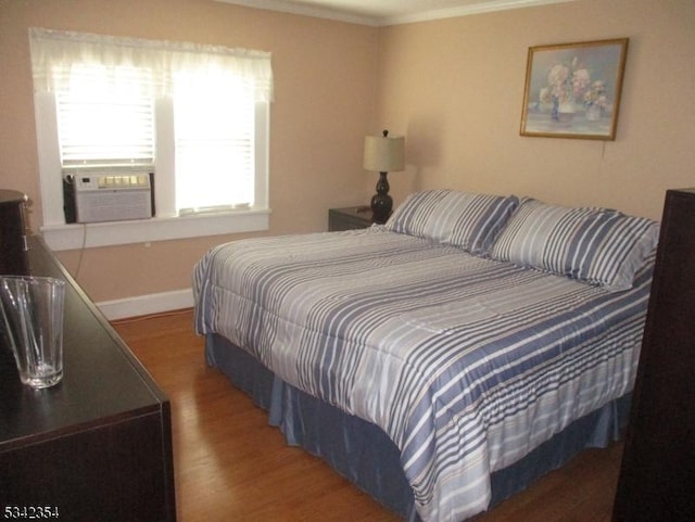 bedroom with ornamental molding, cooling unit, wood finished floors, and baseboards