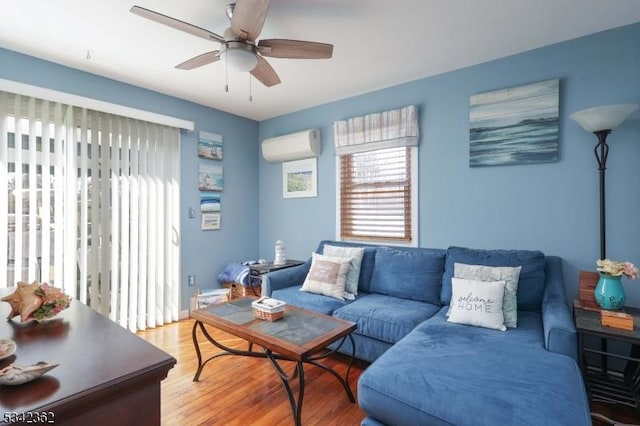 living area featuring light wood-style floors, an AC wall unit, and a ceiling fan