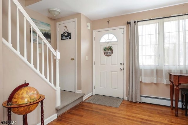 foyer featuring baseboards, stairway, baseboard heating, and wood finished floors