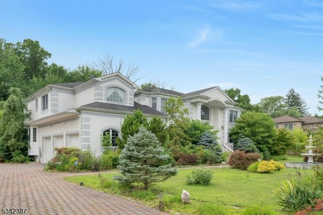 view of front facade featuring a garage, a front lawn, and decorative driveway