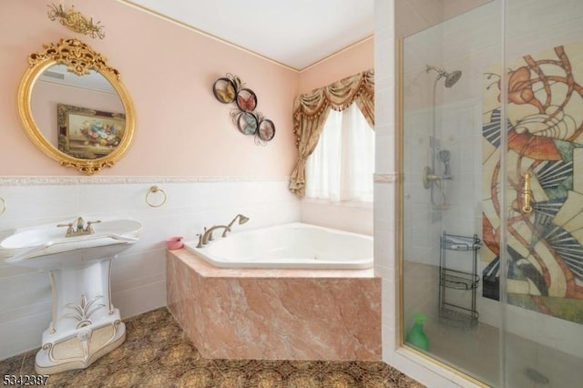 full bathroom featuring a wainscoted wall, a shower stall, a bath, and tile walls