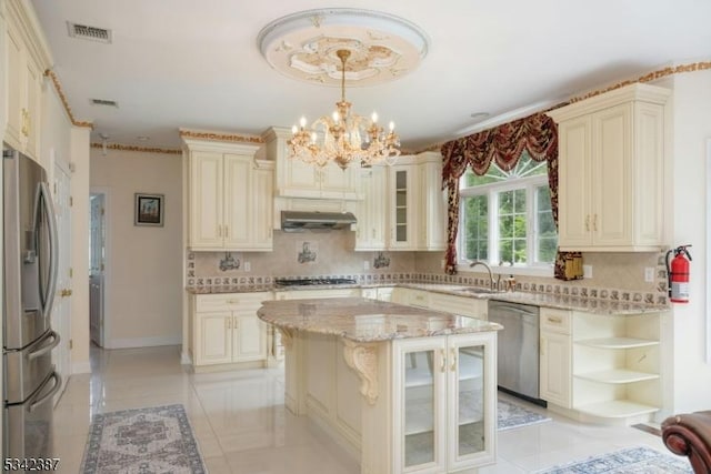 kitchen featuring cream cabinetry, appliances with stainless steel finishes, visible vents, and light stone countertops