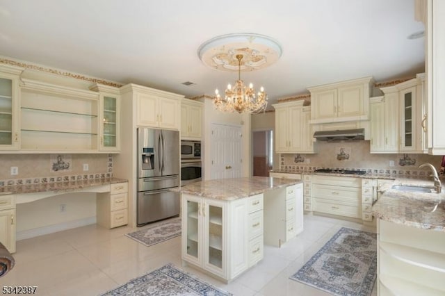 kitchen featuring tasteful backsplash, built in study area, cream cabinets, stainless steel appliances, and a sink