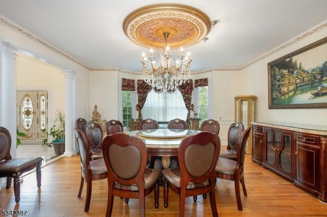 dining room with light wood-style floors, decorative columns, and a chandelier