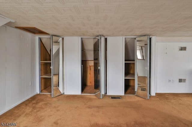 unfurnished bedroom featuring carpet floors, visible vents, and wood walls