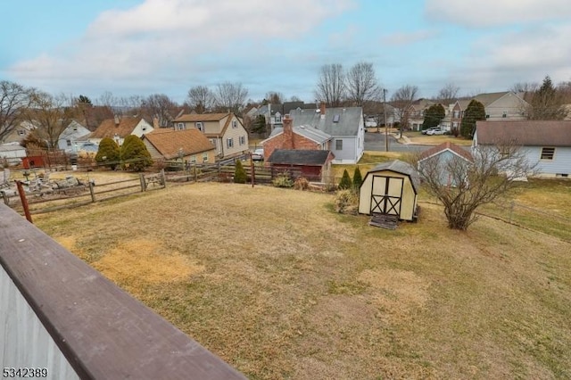 view of yard with a storage unit, an outdoor structure, a fenced backyard, and a residential view