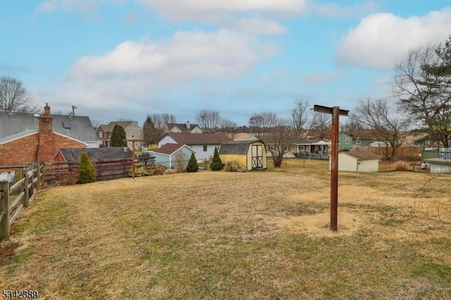 view of yard featuring an outbuilding, fence, a residential view, and a storage unit