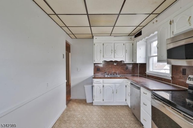 kitchen with baseboards, white cabinets, appliances with stainless steel finishes, decorative backsplash, and dark countertops