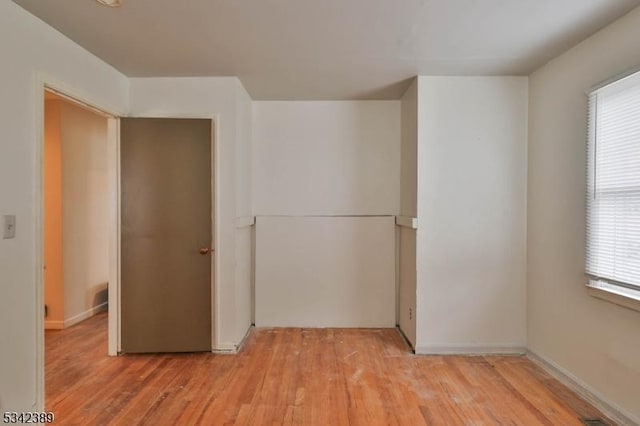 unfurnished room featuring visible vents, light wood-style flooring, and a healthy amount of sunlight