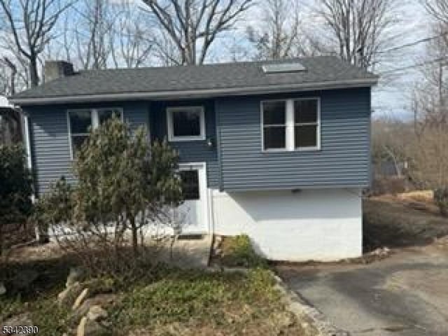 view of front of home with driveway, an attached garage, and a chimney