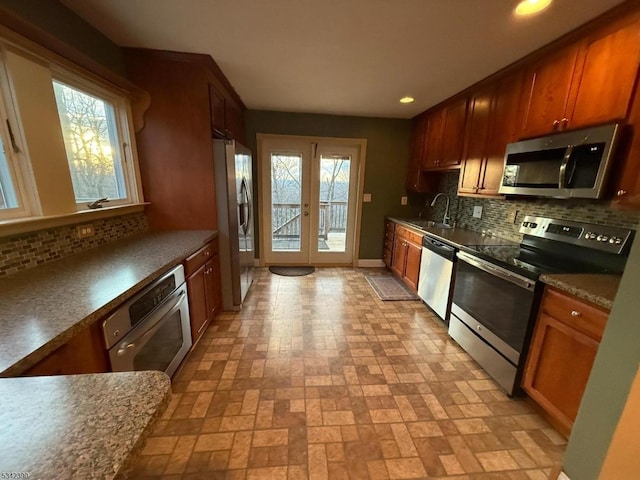 kitchen featuring appliances with stainless steel finishes, french doors, a sink, and tasteful backsplash